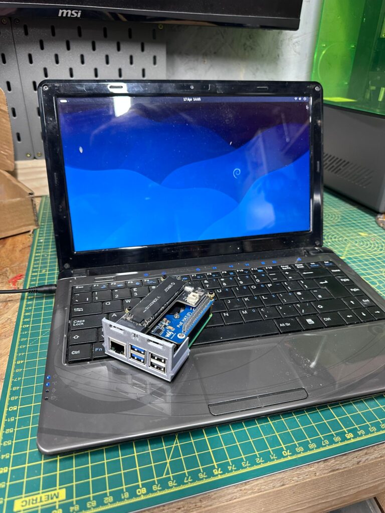 Advent Verona laptop running Debian with a Raspberry Pi 5 on the keyboard for scale