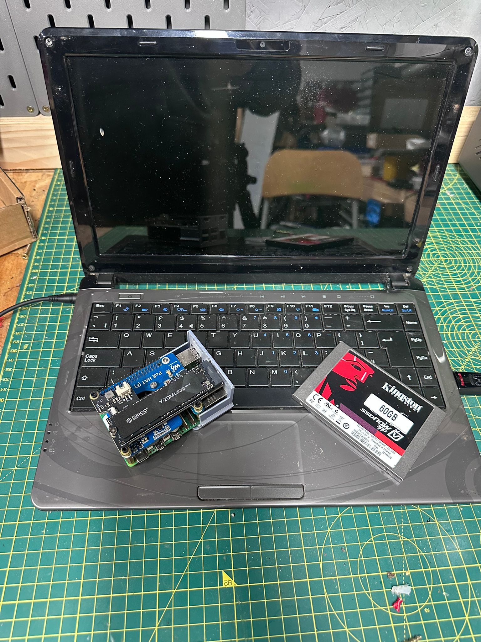 Advent Verona laptop, Raspberry Pi 5 and a SATA SSD laid out on the keyboard before install