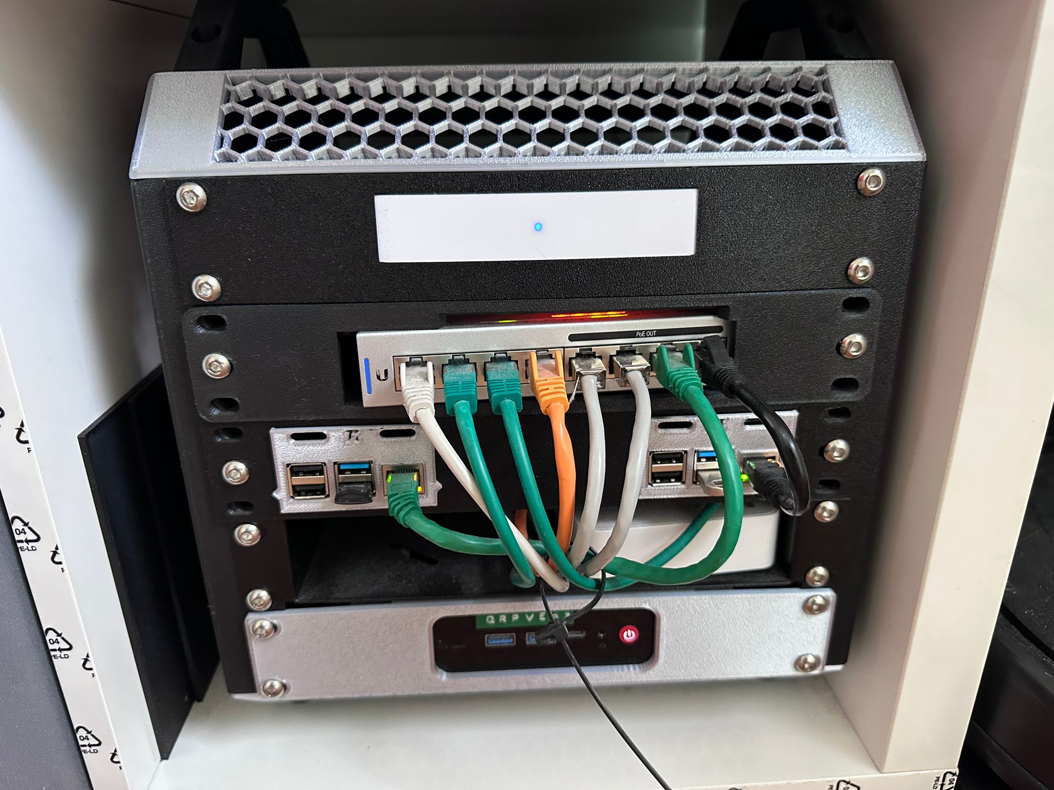 IKEA Kallax repurposed as a home server rack with UniFi gateway, PoE switch, Raspberry Pi and a mini-PC dressed in colour-coded cabling