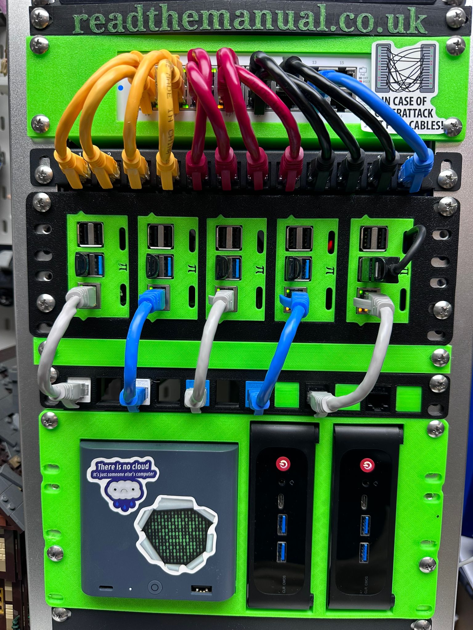 3D-printed green Raspberry Pi cluster rack branded ReadTheManual.co.uk with colour-coded cables and the There is no cloud sticker