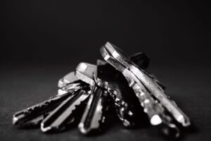 A pile of metal keys on a dark surface, representing access accumulated across a career